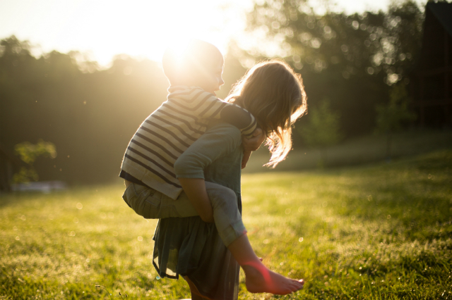 Gril carries a child on her back © Unsplash/Jenn Evelyn-Ann
